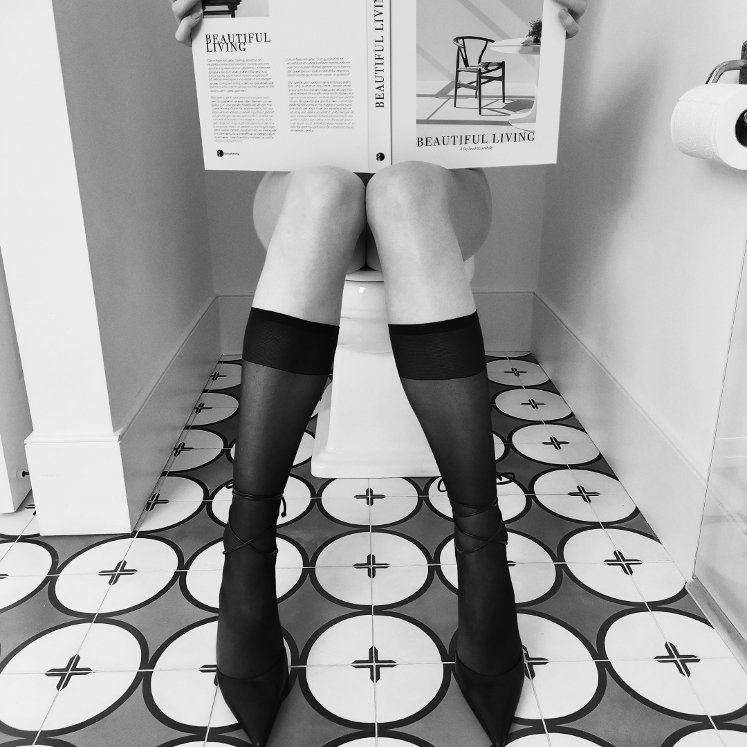 woman sitting on a toilet reading a book